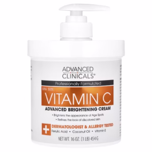 White jar of Advanced Clinicals Vitamin C Brightening Cream on clean white background. Gold label highlights "Vitamin C + Coconut Oil." Cream scooped on fingertips shows velvety texture. Ideal for fading dark spots and hydrating skin in tropical climates.