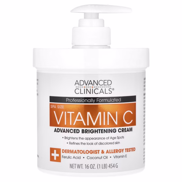 White jar of Advanced Clinicals Vitamin C Brightening Cream on clean white background. Gold label highlights "Vitamin C + Coconut Oil." Cream scooped on fingertips shows velvety texture. Ideal for fading dark spots and hydrating skin in tropical climates.