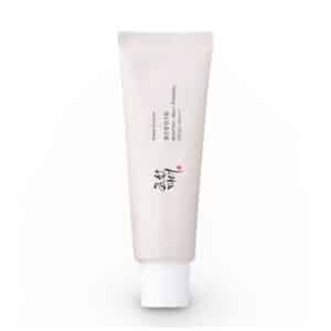 Front view of Beauty of Joseon Relief Sun Rice + Probiotics SPF50 PA++++ sunscreen tube (50ml) on white background. Gold Korean text accents the white packaging, with visible labels: "30% Rice Extract," "Probiotics," and "SPF50+ PA++++." A pearl-sized dollop of the creamy, off-white formula is shown blending seamlessly into skin
