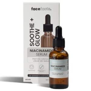 Amber glass dropper bottle of “Face Facts Soothe + Glow Niacinamide Serum” standing in front of its lilac‑and‑white retail box on a clean white background