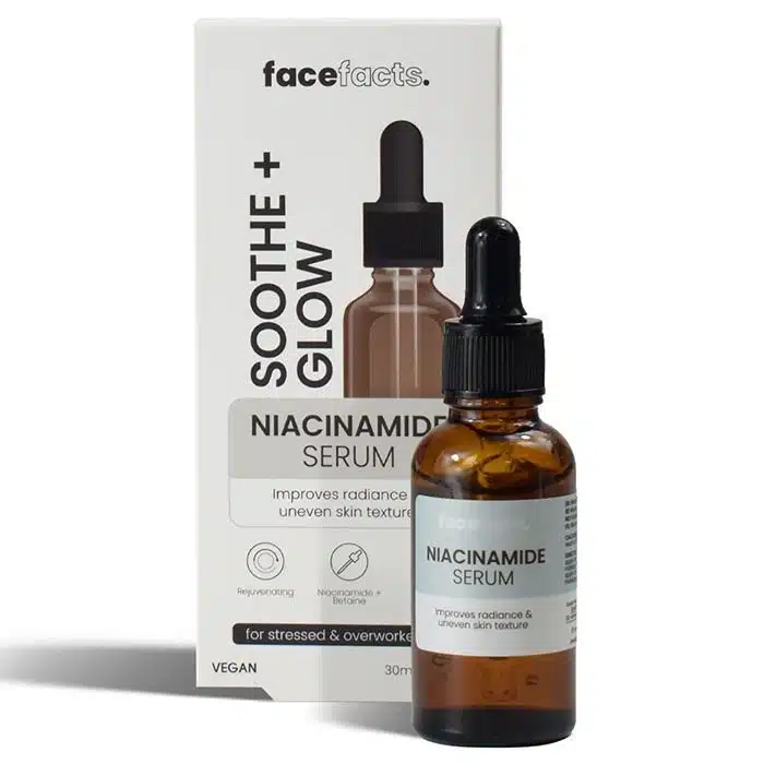 Amber glass dropper bottle of “Face Facts Soothe + Glow Niacinamide Serum” standing in front of its lilac‑and‑white retail box on a clean white background