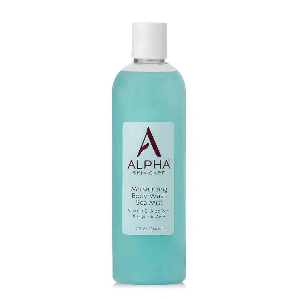 Clear white-background image of a 12 fl oz bottle labeled “Alpha Skin Care Moisturizing Body Wash – Sea Mist.” The burgundy Alpha “A” logo sits above product claims: 10 % glycolic AHA, Vitamin E & Aloe Vera. Aqua wave graphic suggests its refreshing, ocean-inspired scent.