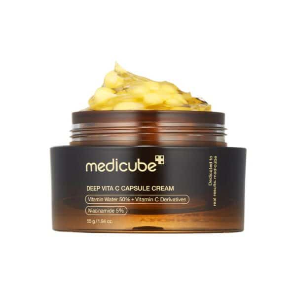 Open jar of Medicube Deep Vita C Capsule Cream 55 g on white background, showing translucent gel studded with golden vitamin C capsules alongside silver lid, illustrating dual-texture formula for brightening and hydration.