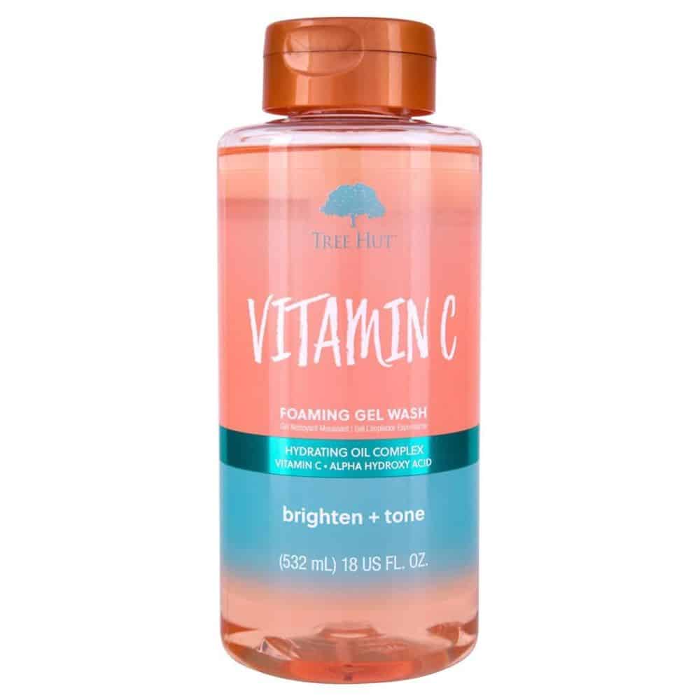 Clear bottle of Tree Hut Vitamin C Foaming Gel Wash (18 fl oz) standing upright on a white background; label features orange-yellow accents and citrus imagery, showcasing the brightening, vitamin C-infused body wash for radiant, hydrated skin.
